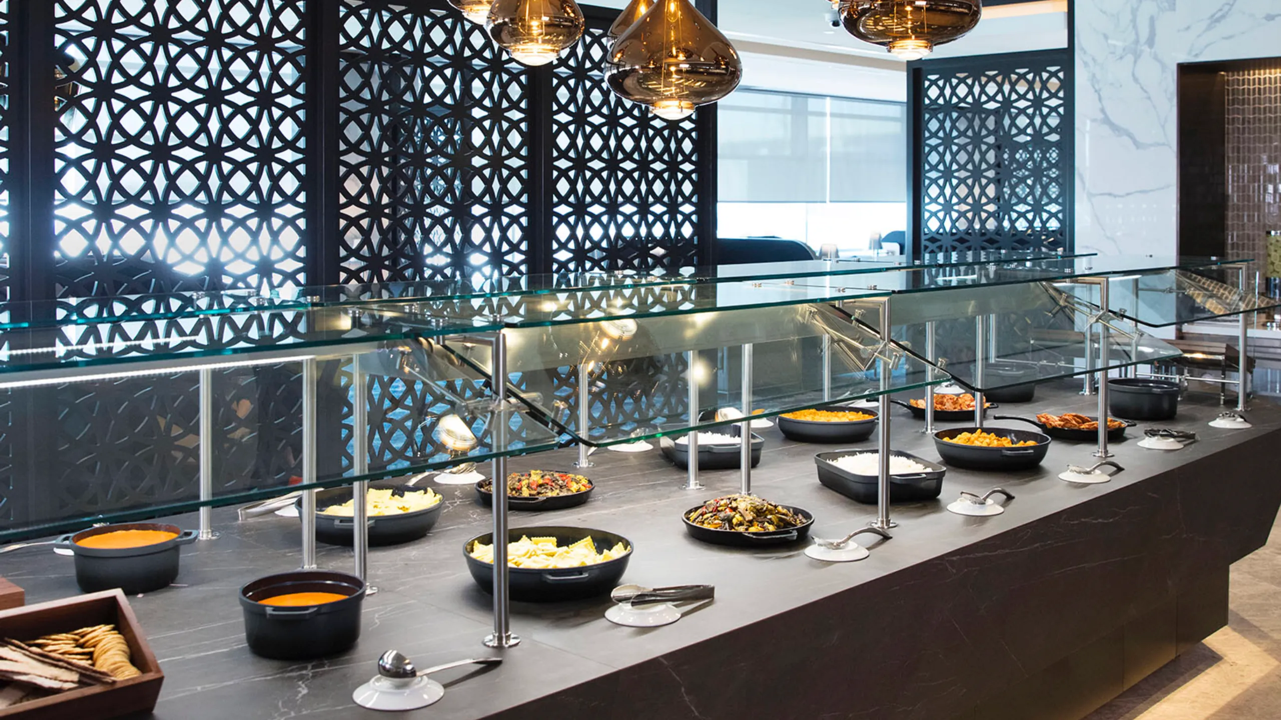 Induction serving counter beside patterned screens and large windows