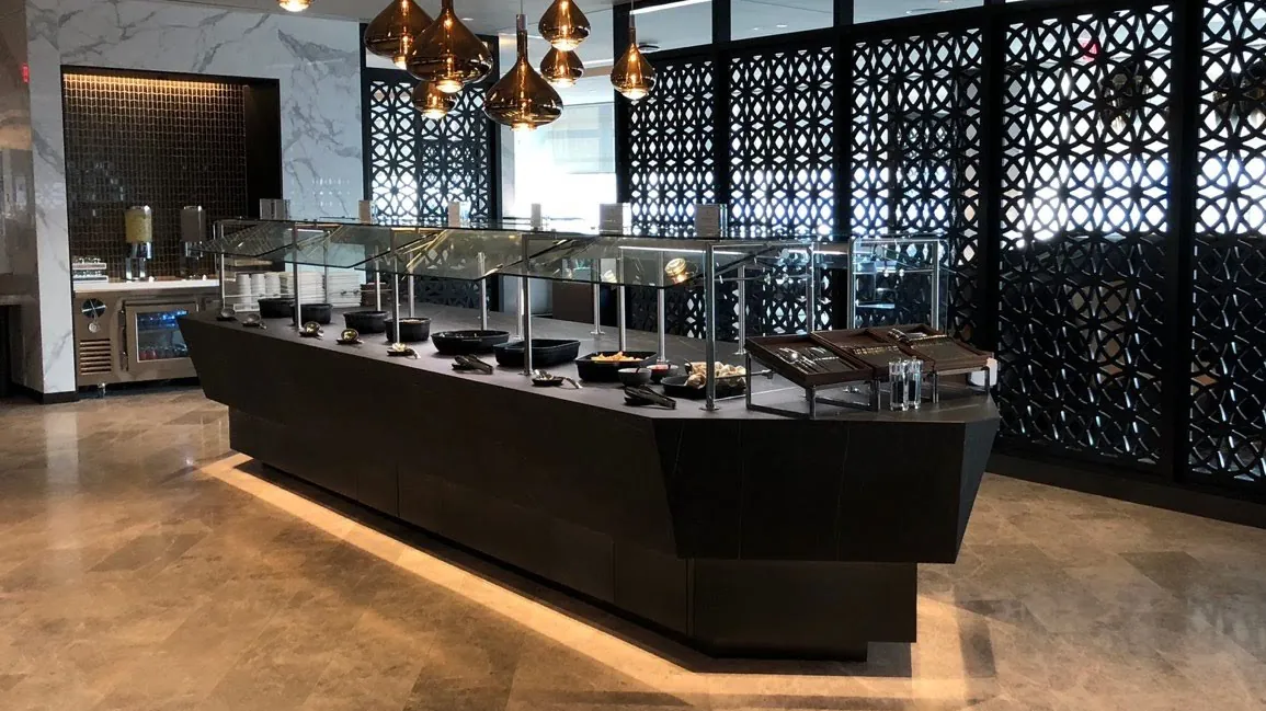 Dark porcelain serving island with induction stations, patterned screens and copper pendants