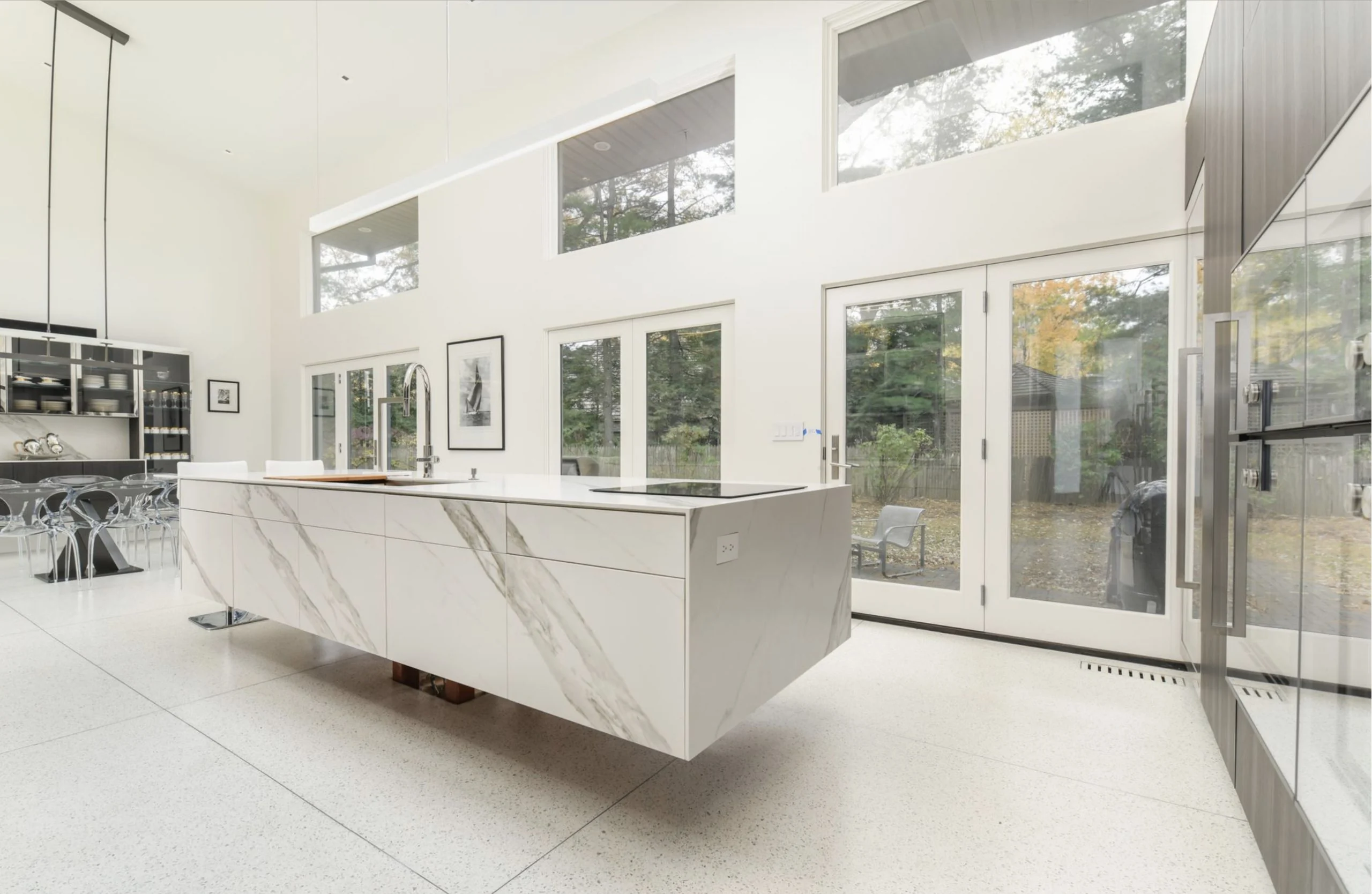 Bright kitchen with a long white island and floor to ceiling windows