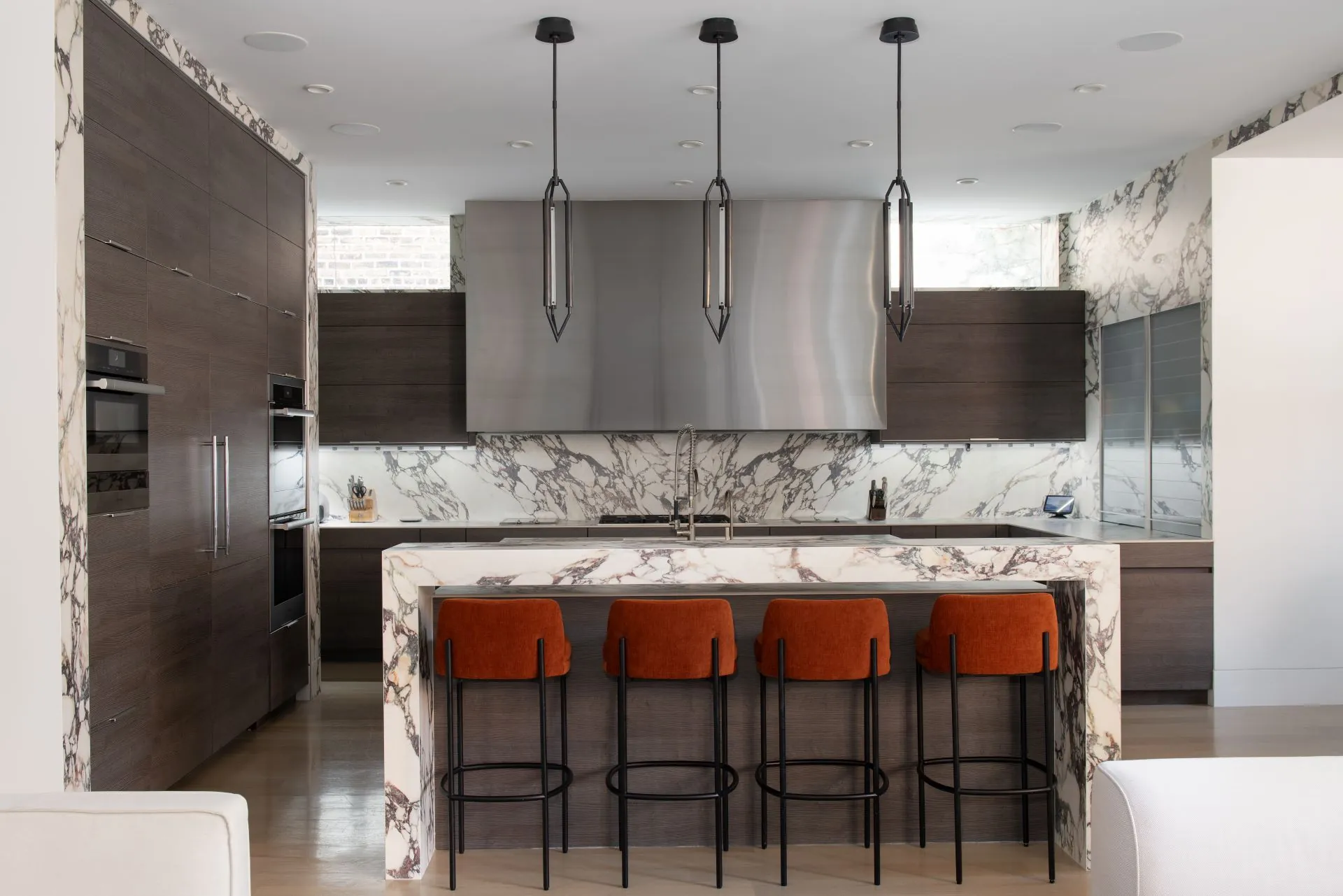 Kitchen island with bold veining and rust coloured stools