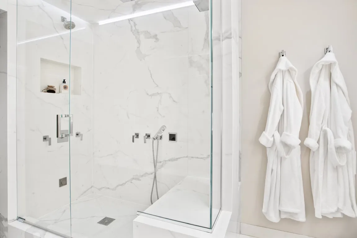 Pale veined shower walls with a glass enclosure