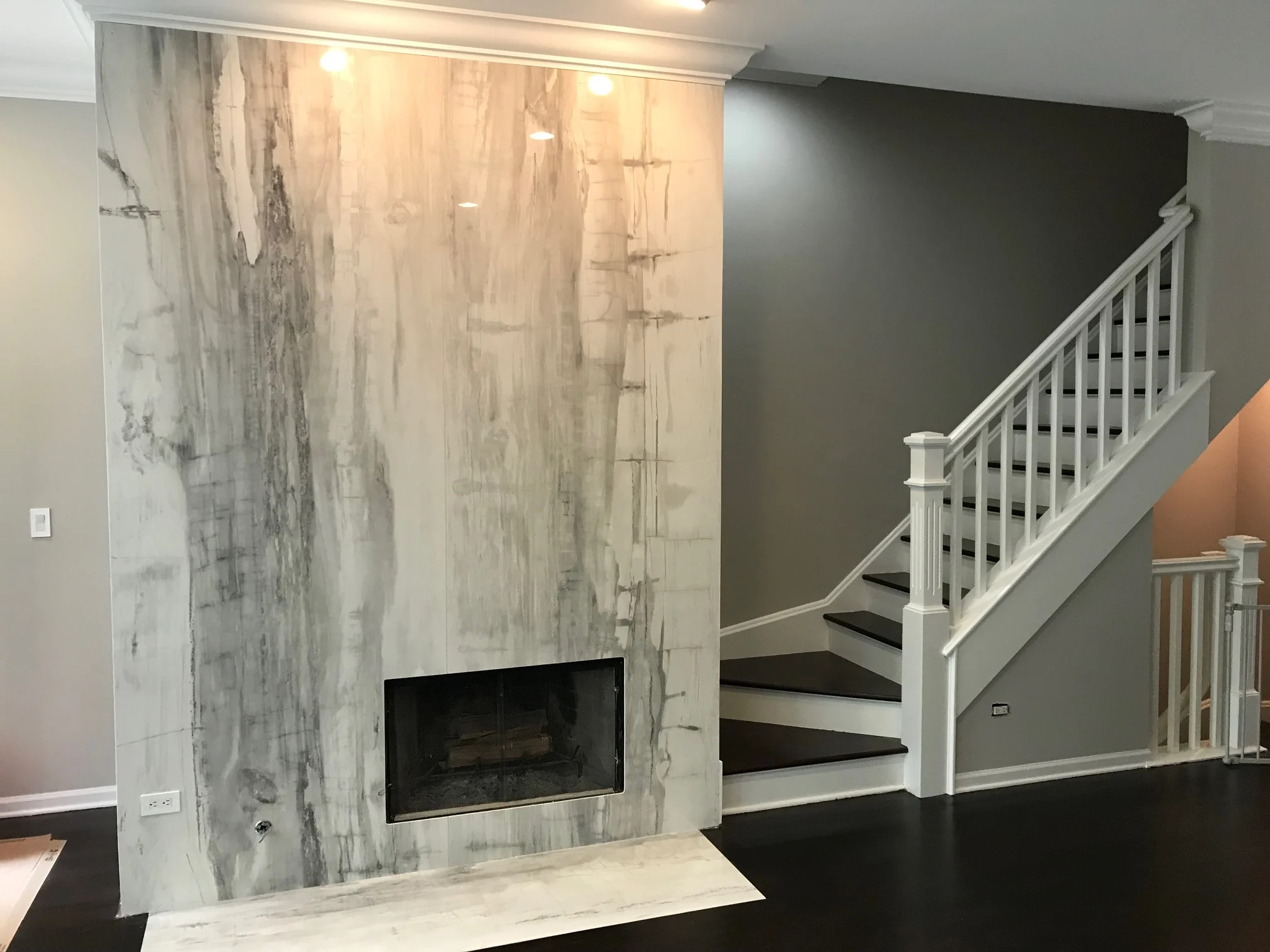 Tall veined fireplace surround beside a staircase